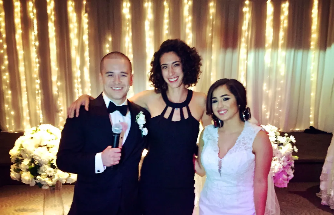 Merav with the newlyweds under string lights